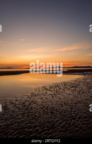 Coucher de soleil sur la plage de Harlech avec ciel bleu et mer calme. Banque D'Images