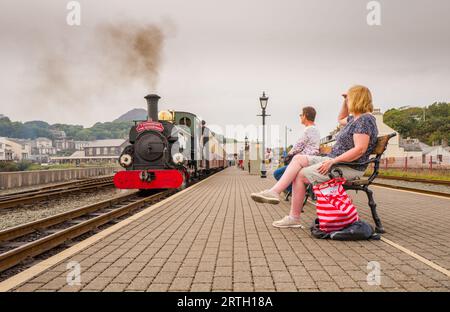 Les passagers attendent assis sur le quai de la gare de Porthmadoc pour le train à vapeur. Banque D'Images