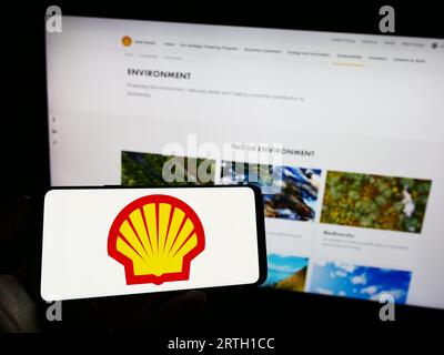 Personne détenant un smartphone avec le logo de la société pétrolière et gazière britannique Shell plc sur l'écran devant le site Web. Concentrez-vous sur l'affichage du téléphone. Banque D'Images