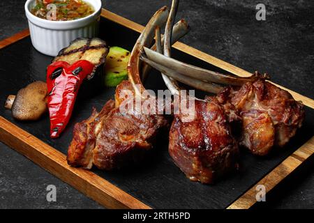 carré d'agneau aux légumes grillés et sauce épicée, sur un tableau Banque D'Images