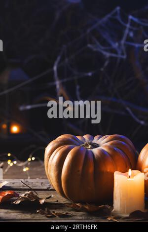 Image verticale de citrouilles, bougies et décorations en toile d'araignée avec espace de copie sur fond noir Banque D'Images