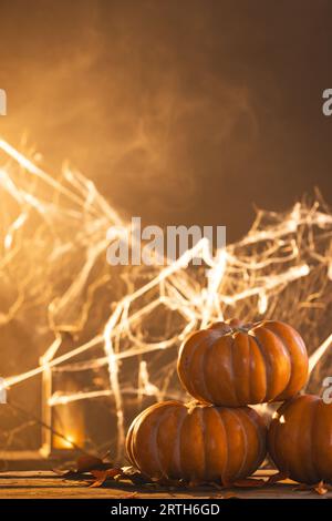 Image verticale de citrouilles et décorations en toile d'araignée avec espace de copie sur fond orange Banque D'Images