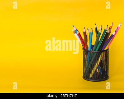 porte-crayon de boîte de filet en métal en forme de cylindre isolé sur fond jaune. beaucoup de stylo coloré , concept d'éducation , zone d'espace de copie. Photo de haute qualité Banque D'Images