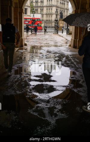 LONDRES - 24 avril 2023 : admirez la beauté de Londres par un jour de pluie avec un bus à impériale emblématique, des flaques d'eau et une arche Horse Guards Parade. Banque D'Images