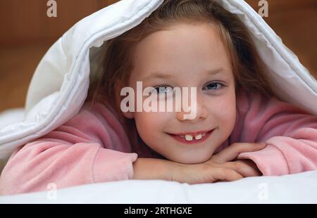 Mignon adorable petite fille blonde caucasienne couchée dans le lit sur un oreiller blanc Banque D'Images