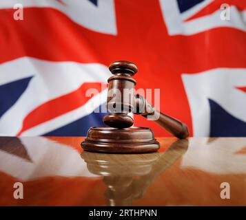 Marteau en bois d'acajou sur une table en bois brillant. Drapeau du Royaume-Uni en arrière-plan Banque D'Images