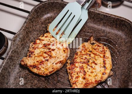 Steak juteux grillé avec des épices sur une poêle à gril, la fille se retourne avec une spatule sur le poêle Banque D'Images