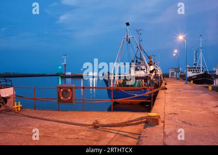 Bateaux de pêche au crépuscule amarré à la jetée en béton dans la mer Baltique au port de Wladyslawowo en Pologne Banque D'Images