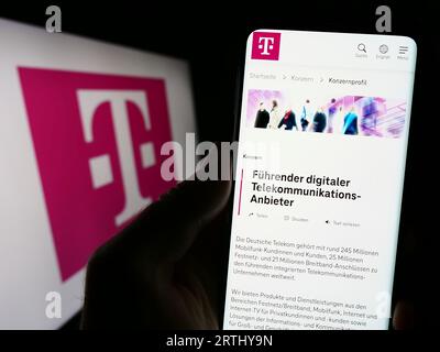 Personne détenant un téléphone portable avec la page Web de la société de télécommunications Deutsche Telekom AG sur l'écran avec logo. Concentrez-vous sur le centre de l'écran du téléphone. Banque D'Images