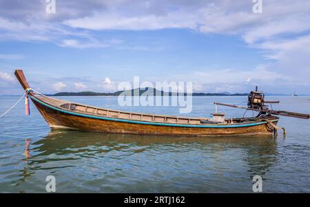 Bateau Longtail attendant les passagers sur la belle île de Ko Lanta, Thaïlande. Les nuages et le bateau encadrent un morceau de ciel bleu un espace blanc Banque D'Images