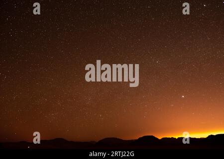 Observation des étoiles dans le désert de Wadi Rum en Jordanie. Des dizaines de camps de Beduin offrent un hébergement touristique dans le désert sous un ciel nocturne clair après le coucher du soleil Banque D'Images