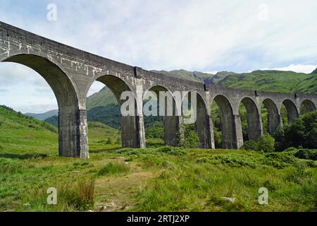 Le pont de chemin de fer par Harry Potter filmant la célébrité. Sur le pont, le Poudlard Express rouge va en direction de l'école de magie. IT Banque D'Images