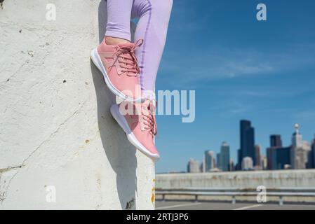 gros plan de baskets roses sur un ciel bleu et un fond d'horizon de la ville, concept de fitness Banque D'Images