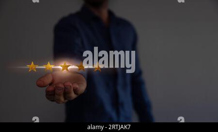 Concept de satisfaction et de service à la clientèle. Homme d'affaires tenant l'écran virtuel les cinq étoiles pour montrer la satisfaction ou le service ou donner le taux. Banque D'Images