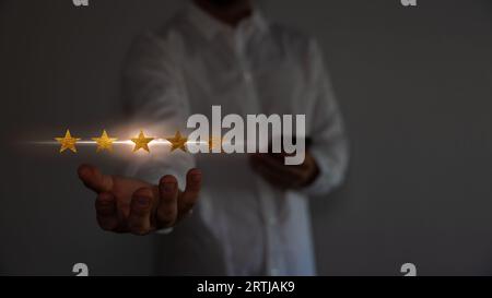 Concept de satisfaction et de service à la clientèle. Homme d'affaires tenant l'écran virtuel les cinq étoiles pour montrer la satisfaction ou le service ou donner le taux. Banque D'Images