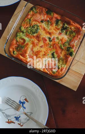 Frittata aux épinards, poisson rouge et fromage sur table en bois. Portion sur une assiette. Oeufs brouillés sur la table en bois. Banque D'Images