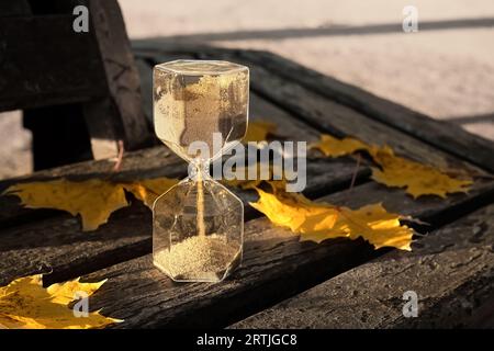 Sablier avec des feuilles tombées sur le banc dans le parc, closeup Banque D'Images