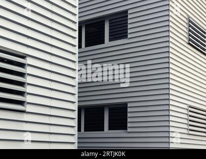 Un gros plan d'une façade de bâtiment minimaliste et moderne, mettant en valeur l'interaction de panneaux gris élégants et de fenêtres rectangulaires lisses. Mise au point sélective. Banque D'Images