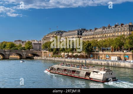 Paris, France - 10 août 2023 : bateau-mouche avec des touristes naviguant sur la Seine sur le front de la voie Georges Pompidou en arrière-plan Pont neuf Banque D'Images