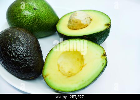 Avocat vert tranché sur fond blanc. Morceaux de légumes verts sur une assiette blanche. Nourriture délicieuse pour un végétalien. Banque D'Images