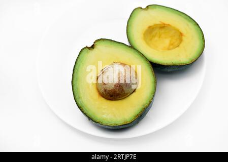 Avocat vert tranché sur fond blanc. Morceaux de légumes verts sur une assiette blanche. Nourriture délicieuse pour un végétalien. Banque D'Images