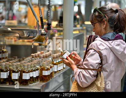 Femme examinant le pot d'huile d'olive avec des herbes et des épices pour la voile Banque D'Images