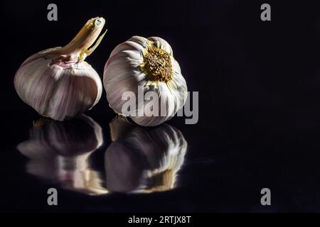 Goiania, Goias, Brésil – 24 mai 2023 : deux têtes d’ail sur une surface noire brillante. Banque D'Images