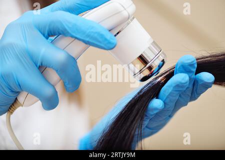 médecin cosmetologue dermatologue diagnostique l'état des cheveux du patient à l'aide d'un dispositif spécial - un trichoscope. Banque D'Images