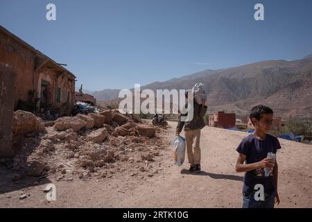 Le 12 septembre 2023, Talat n'Yaaqoub, Maroc : un villageois est vu transportant de l'aide humanitaire à côté d'une maison endommagée dans le village, Talat n'Yaaqoub. Les sauveteurs locaux et internationaux sont sur leur dernière strade de leur mission dans le village, Talat n'Yaaqoub, épicentre du tremblement de terre désastreux au Maroc et au sud de Marrakech, alors que les «72 heures dorées» pour sauver les survivants sont passées. Les villages de la région montagneuse de l'Atlas ont le plus souffert du tremblement de terre. Les membres de la famille de la victime accusent l'accès difficile à la zone de montagne et la lenteur de la réponse du gouvernement ont obstr Banque D'Images