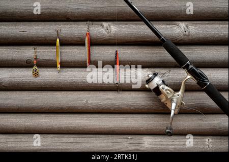 roue à filer et tige avec des leurres douillets accrochés sur un mur gris de stocks de bois Banque D'Images