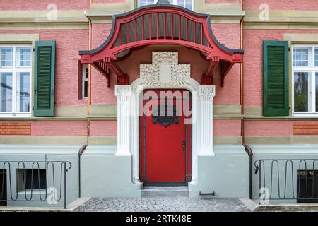 Entrée de la maison de sécession. Porte d'entrée rouge avec décor de style Art Nouveau, architecture urbaine suisse rétro. Portes urbaines et urbaines. Banque D'Images