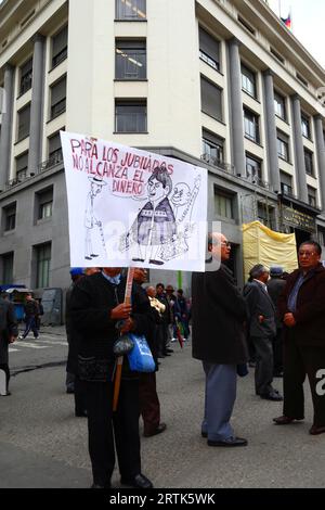 Des enseignants retraités tiennent une caricature du président bolivien Evo Morales Ayma tenant des sacs d'argent liquide à un barrage routier dans le centre-ville lors d'une manifestation réclamant une augmentation de leurs paiements de pension, la Paz, Bolivie. Banque D'Images