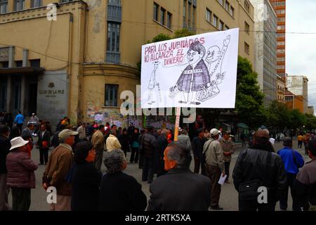 Des enseignants retraités tiennent une caricature du président bolivien Evo Morales Ayma tenant des sacs d'argent liquide à un barrage routier dans le centre-ville lors d'une manifestation réclamant une augmentation de leurs paiements de pension, la Paz, Bolivie. Banque D'Images