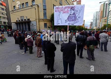 Des enseignants retraités tiennent une caricature du président bolivien Evo Morales Ayma tenant des sacs d'argent liquide à un barrage routier dans le centre-ville lors d'une manifestation réclamant une augmentation de leurs paiements de pension, la Paz, Bolivie. Banque D'Images