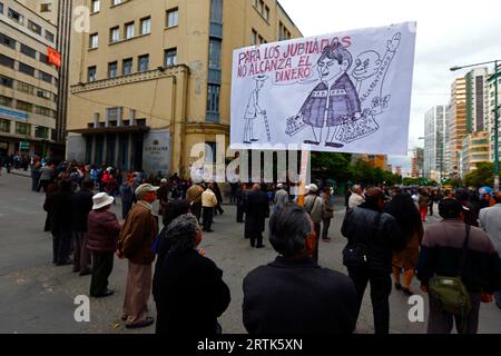 Des enseignants retraités tiennent une caricature du président bolivien Evo Morales Ayma tenant des sacs d'argent liquide à un barrage routier dans le centre-ville lors d'une manifestation réclamant une augmentation de leurs paiements de pension, la Paz, Bolivie. Banque D'Images