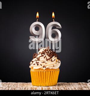 Cupcake d'anniversaire avec bougie numéro 96 - célébration sur fond sombre Banque D'Images