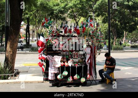 Mexico, Mexique - 6 septembre 2023 : Stall de rue vendant des drapeaux tricolores mexicains, des roues d'épingle, des chapeaux et d'autres articles nationaux Banque D'Images