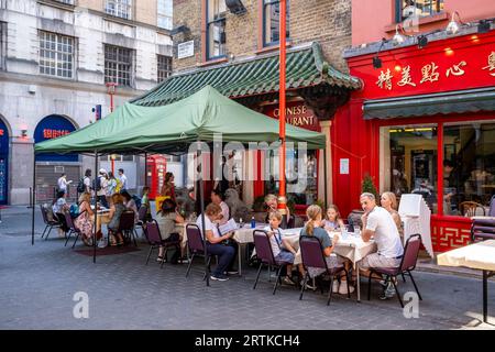 Touristes mangeant à l'extérieur dans Un restaurant chinois à Chinatown, Soho, Londres, Royaume-Uni. Banque D'Images