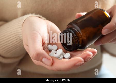 Femme versant des pilules de la bouteille, vue rapprochée Banque D'Images
