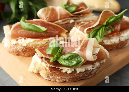 Sandwichs savoureux avec jambon séché et basilic sur planche de bois, gros plan Banque D'Images