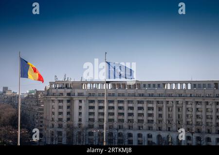 Photo d'un drapeau roumain volant dans les airs à Bucarest, la capitale de la Roumanie, à côté d'un drapeau de l'OTAN. Banque D'Images