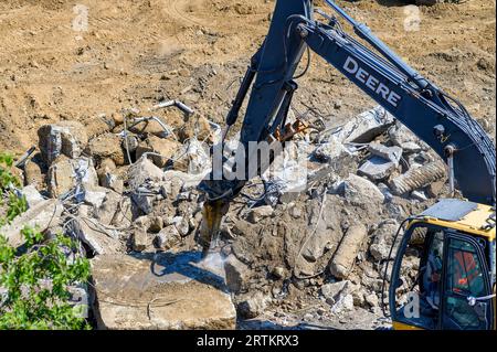 NOUVELLE-ORLÉANS, LA, États-Unis - 13 SEPTEMBRE 2023 : une pelle John Deere équipée d'un marteau hydraulique brise une dalle de béton sur un chantier de démolition Banque D'Images