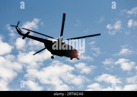 Silhouette d'hélicoptère mi-8 contre le ciel bleu avec des nuages en vol. Banque D'Images