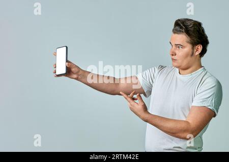 Un homme à bout de bras montre un écran de téléphone sur fond gris, maquette Banque D'Images