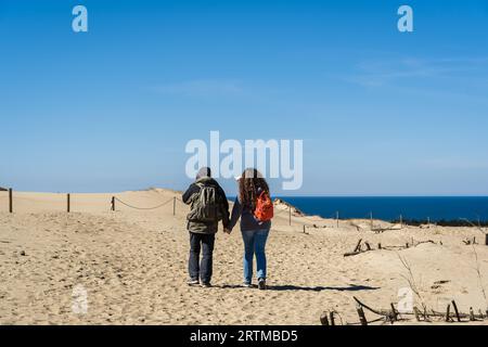 Un couple de touristes routards voyagent à travers les dunes de sable sur les rives de la mer Baltique Banque D'Images