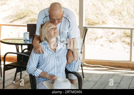 Un homme âgé s'étreint et parle à une femme sur la terrasse d'un café. Un couple âgé. Banque D'Images