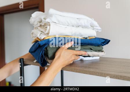 Une grande pile de vêtements après le lavage, la jeune fille prend les vêtements pour se cacher dans le placard. Devoirs Banque D'Images