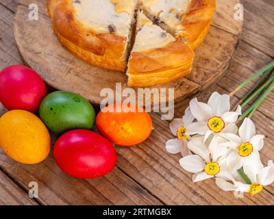 plat traditionnel roumain de pâques cozonac et pasca ou pain sucré et tarte au fromage comme sur la table en bois et les œufs de pâques colorés et les fleurs de côté Banque D'Images