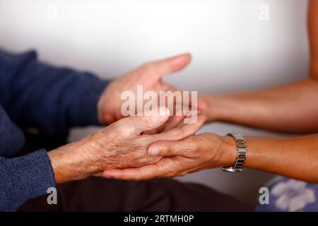 Maison de retraite. Gros plan des assistants de soins main rassurant homme âgé. Banque D'Images