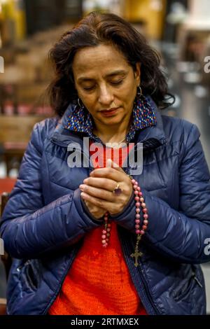 Femme priant dans l'église catholique notre Dame du Finisterre, Bruxelles, Belgique. Banque D'Images